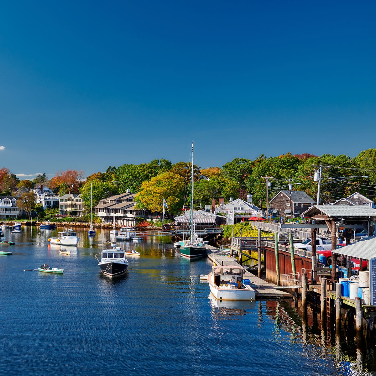Many boats in a bright blue calm harbor in New England.