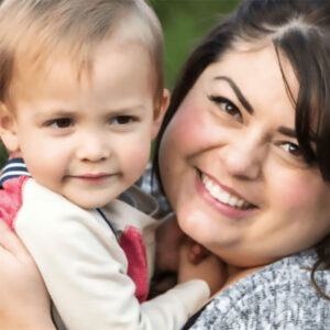 A mother and her baby daughter smile contentedly close to the camera.